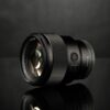 Close-up of a professional camera lens on a reflective black surface, ideal for technology and photography themes.