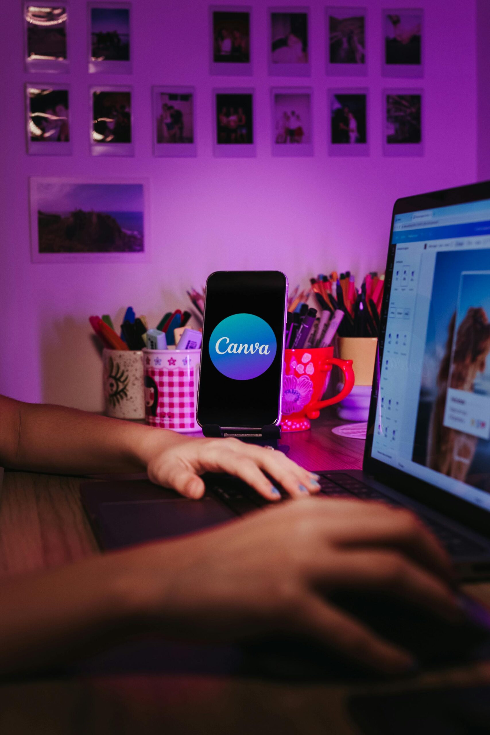 A creative home workspace with a laptop and smartphone displaying Canva, showcasing a vibrant, organized desk setup.