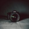 A camera lens in focus against a dark background, highlighting the optical details.
